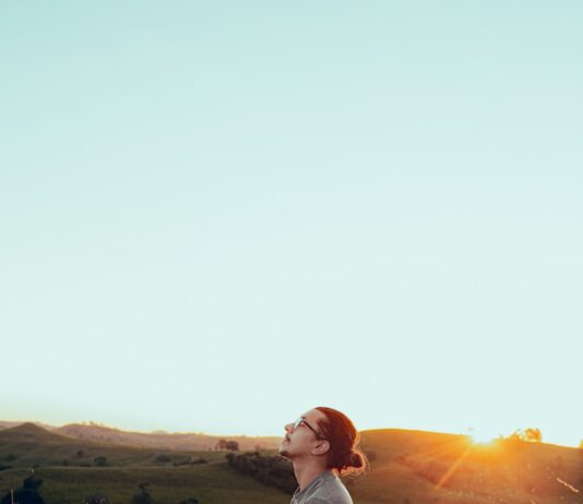 심리적 안정을 위한 7가지 효과적인 습관 man in white shirt sitting on green grass field during sunset