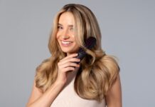 요즘 뜨는 ‘두피·헤어 루틴’, 건강한 머릿결을 위한 실천법은? a woman holding a hair brush in her hand