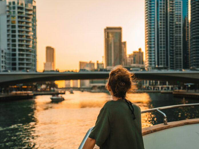 Woman on boat overlooking city skyline at sunset